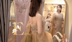 試衣鏡前主婚人媽媽試穿香檳金重手工水鑽晚禮服，搭配透膚披肩展現優雅氣場
