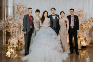 主婚人親家母分別身穿銀灰色流蘇晚禮服與香檳杏色珠工禮服，於婚宴背板前合照