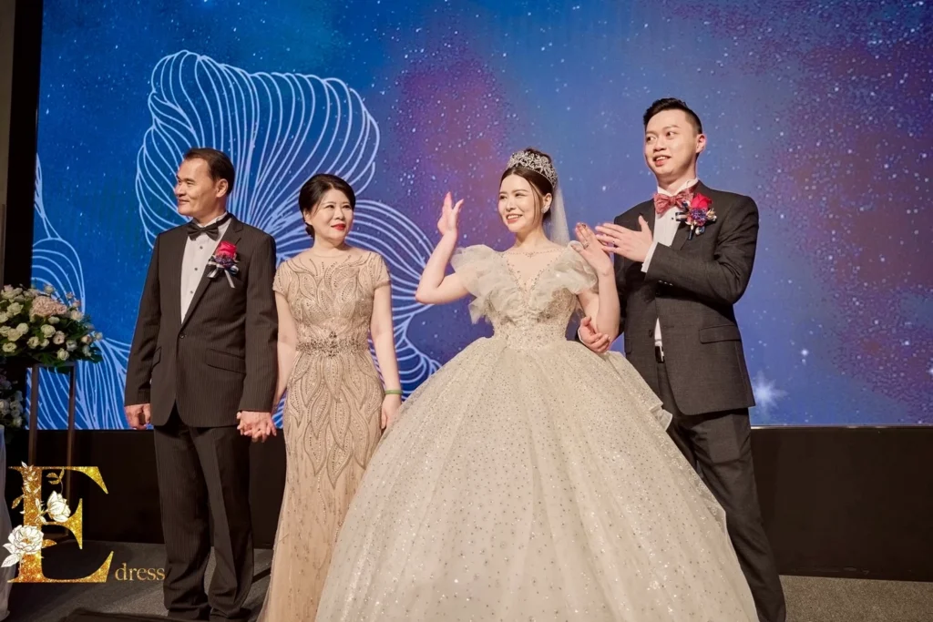 溫馨婚禮時刻：主婚人穿著艾莉禮服舞台上顯瘦剪裁效果與精緻手工珠鑽細節。